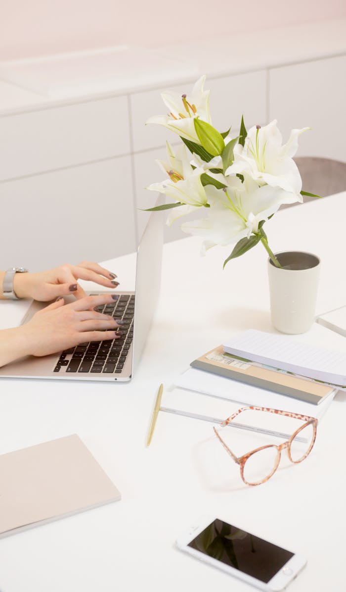 testimonials-img A serene workspace featuring a laptop, flowers, and office supplies on a white desk.